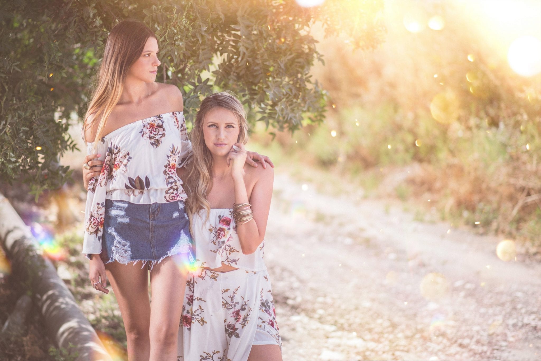 Two ladies standing near a tree with arms around each other