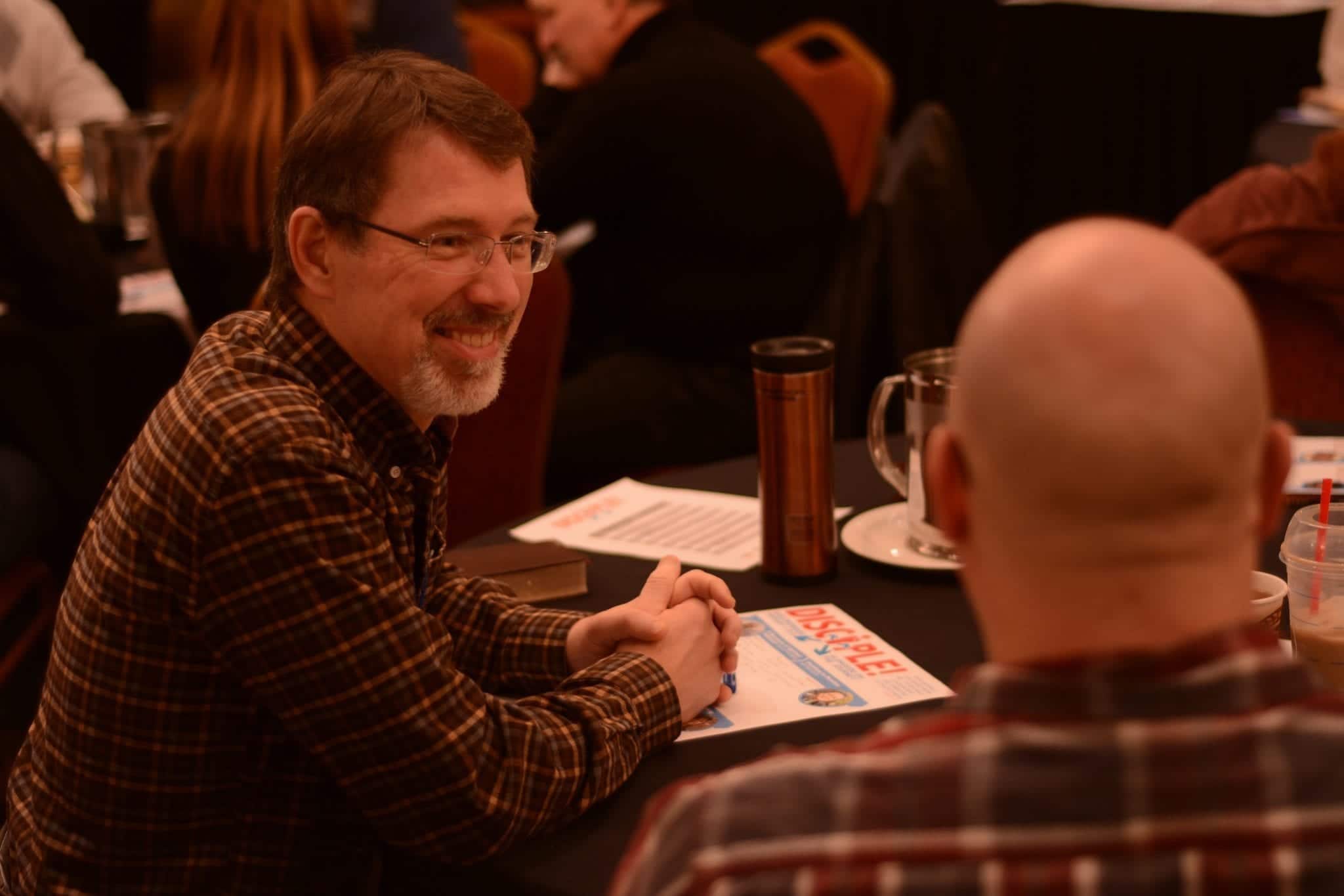 Smiling man at a table talking about discipling