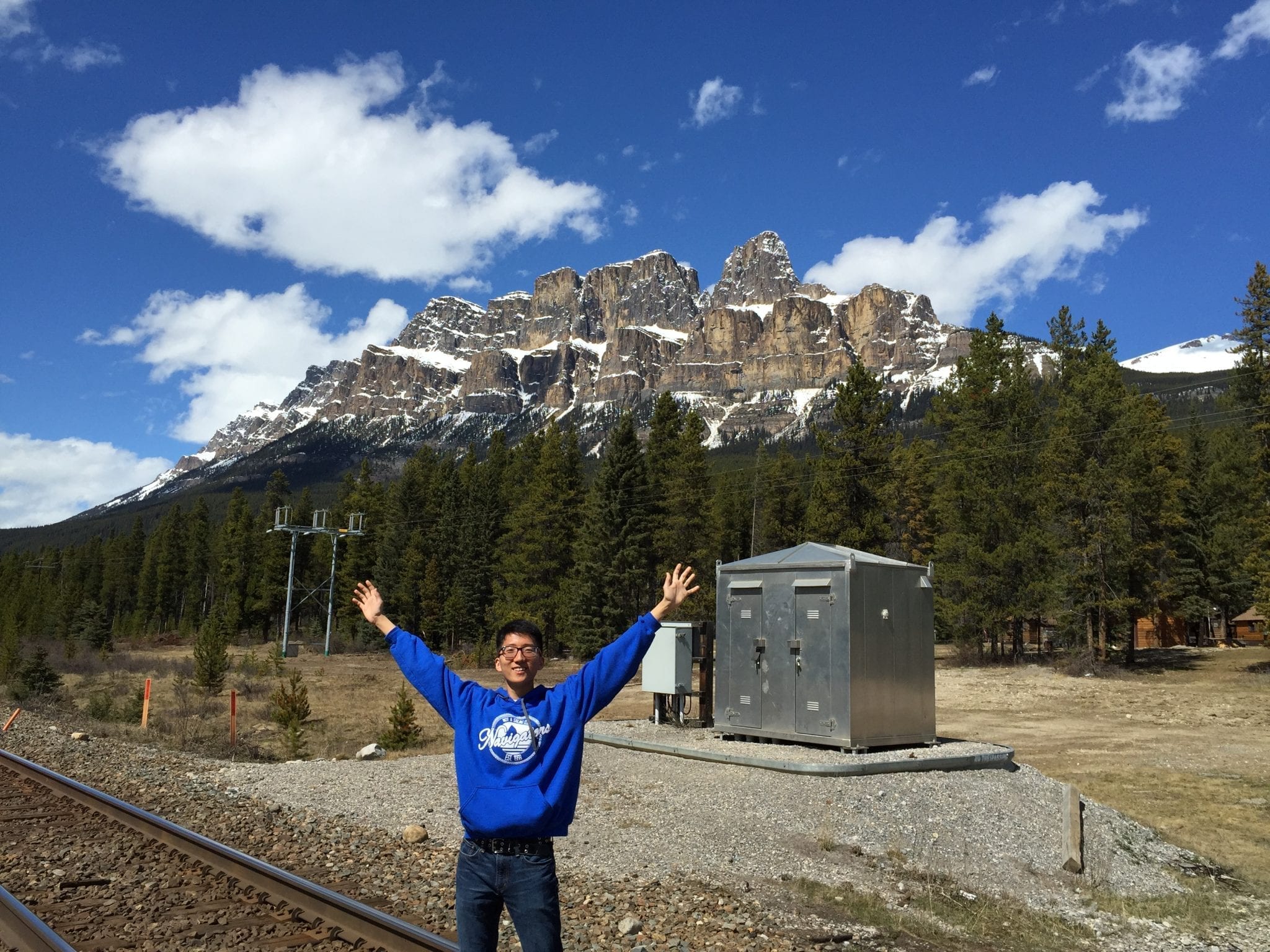 Jeff Yao standing in front of mountains with outstretched arms at Basecamp West